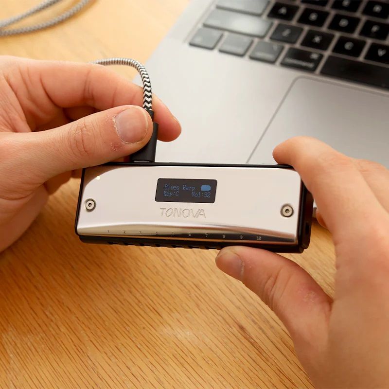 Picture of two hands holding the Tonova MIDI Harmonica