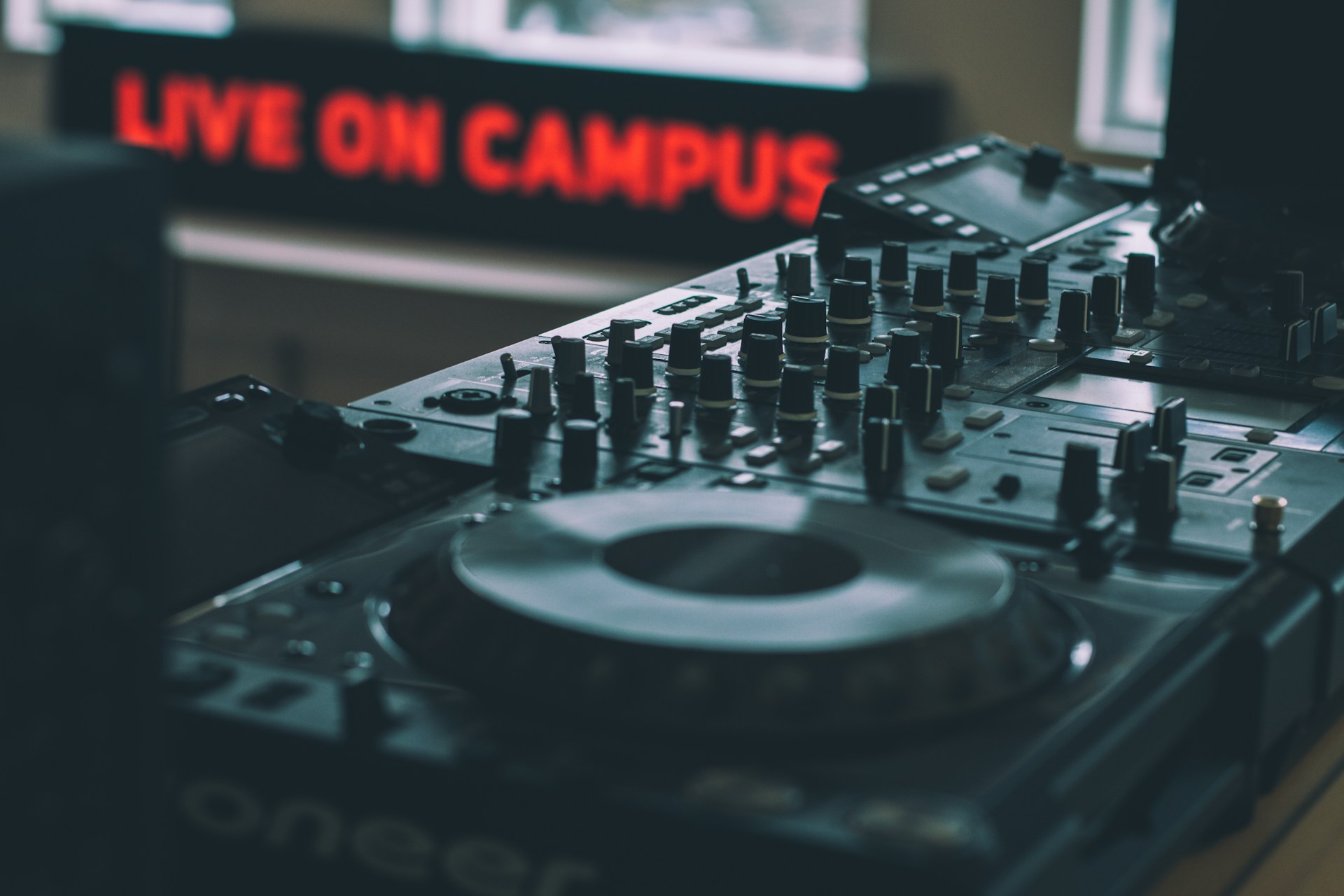 Music electronics with red sign in background "live on campus".