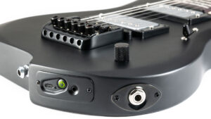 Close-up view of a black electric guitar body showing the bridge, control knob, and input/output ports, including a USB-C port, power button, and a standard 1/4-inch audio jack.