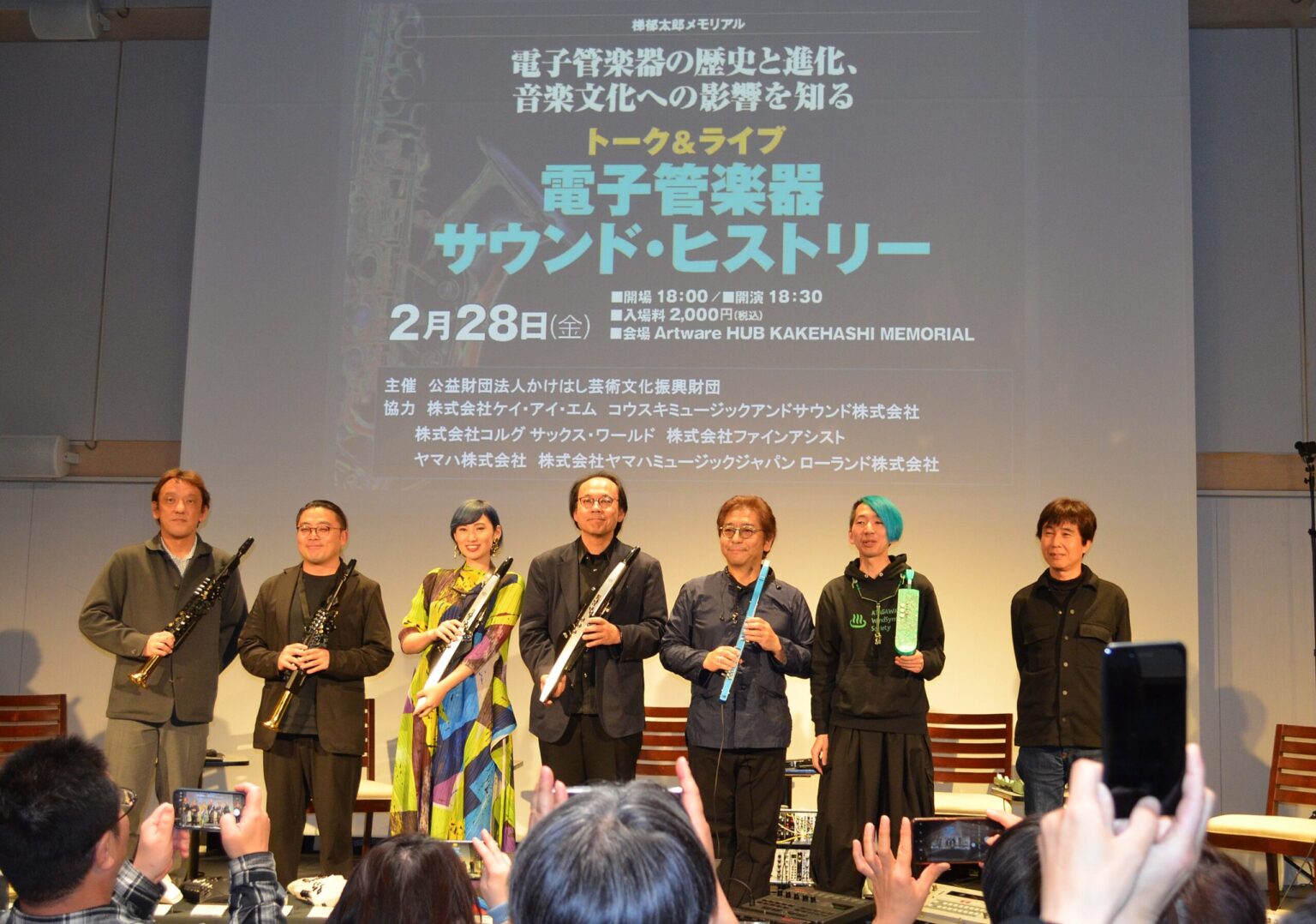 Pictyre of all the participants in the electronic wind instruemnts events standing on stage and holding their various wind controllers