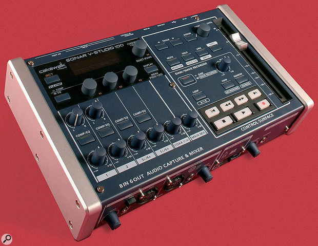 A black and silver Roland SONAR V-Studio 100 audio interface and mixer with various knobs, sliders, and buttons, shown on a red background.