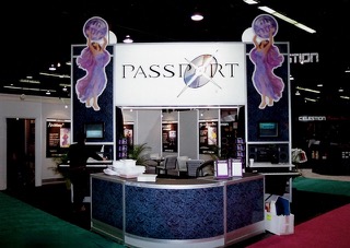 A trade show booth with a large Passport sign, decorated with two purple fairy figures on either side, a counter with materials, and display screens on both sides. The background shows other booths and displays.