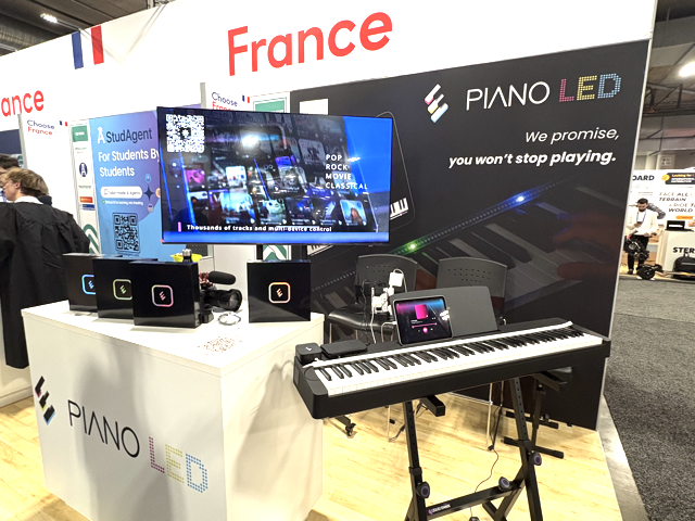 A trade show booth for PIANO LED under a “France” sign features a digital piano, colorful LED displays, promotional screens, and the slogan: “We promise, you won’t stop playing.”.