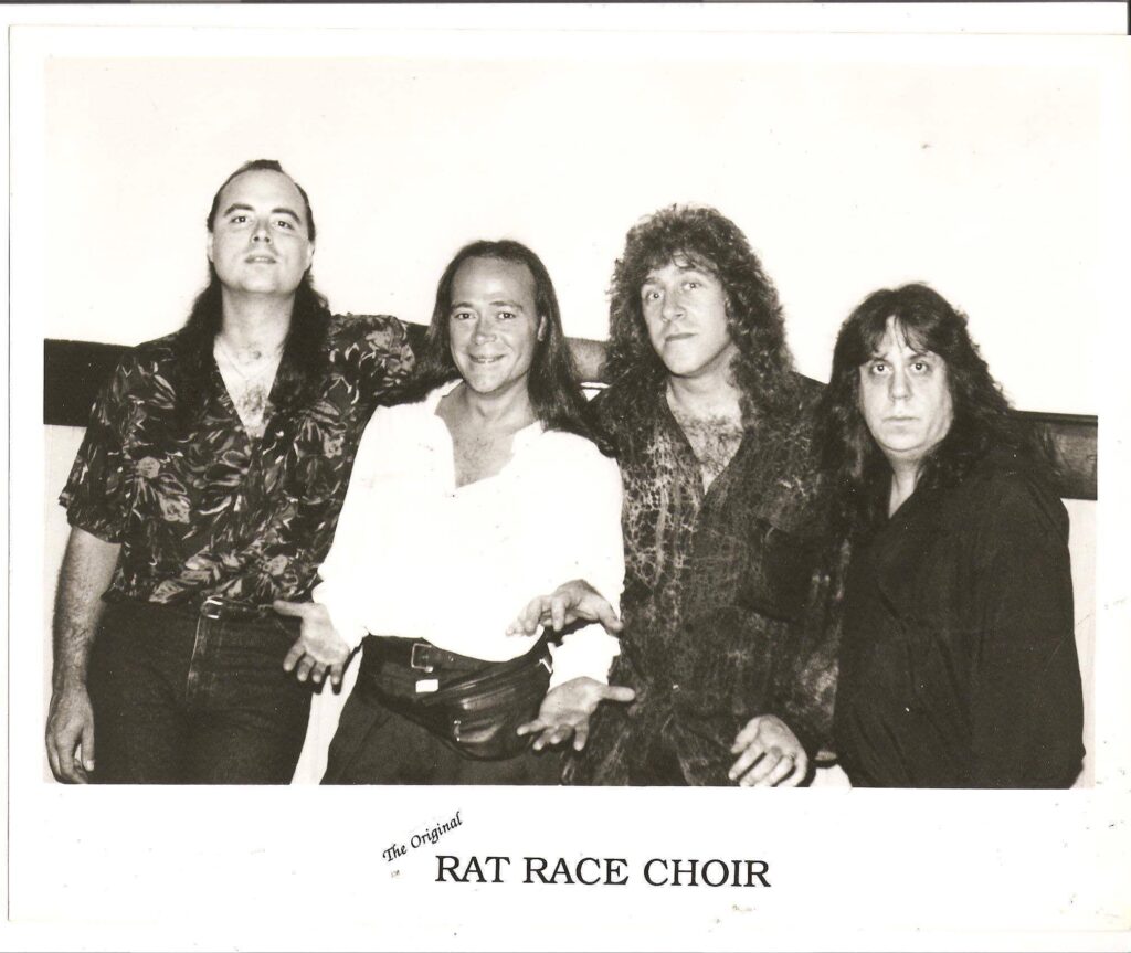 A black and white photo of the band Rat Race Choir, featuring four men with long hair.